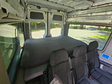 RV rental interior: spacious camper van with bed & 3 passenger seats. View from inside at parking lot.