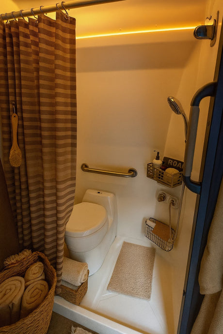 Cozy RV rental wet bath, featuring a toilet, shower, grab bar, and organized amenities for a comfortable road trip experience.