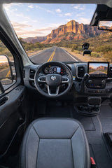 RV rental van interior: Steering wheel and dashboard frame a majestic mountain road and golden sky, ready for an epic road trip.