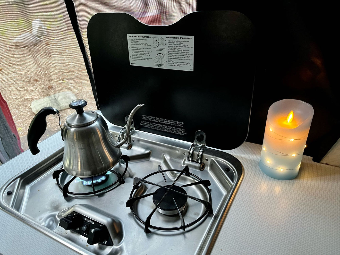  with cooking instructions on the open cover and a cozy LED candle nearby.|Inside a comfortable rv rental: Kitchenette — photo 6