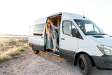 Woman steps out of a white camper van on a sunny day. Ideal for your next outdoor adventure or RV rental.