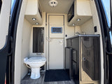Explore this RV rental's well-equipped interior: a compact kitchen with sink/microwave, toilet, and storage inside this camper van.