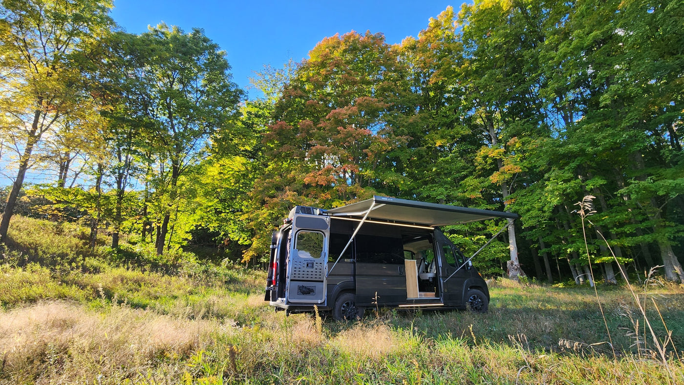 An Airstream RV camper van, perfect for an rv rental, parked in a sunny clearing with vibrant autumn trees and blue sky. — photo 13