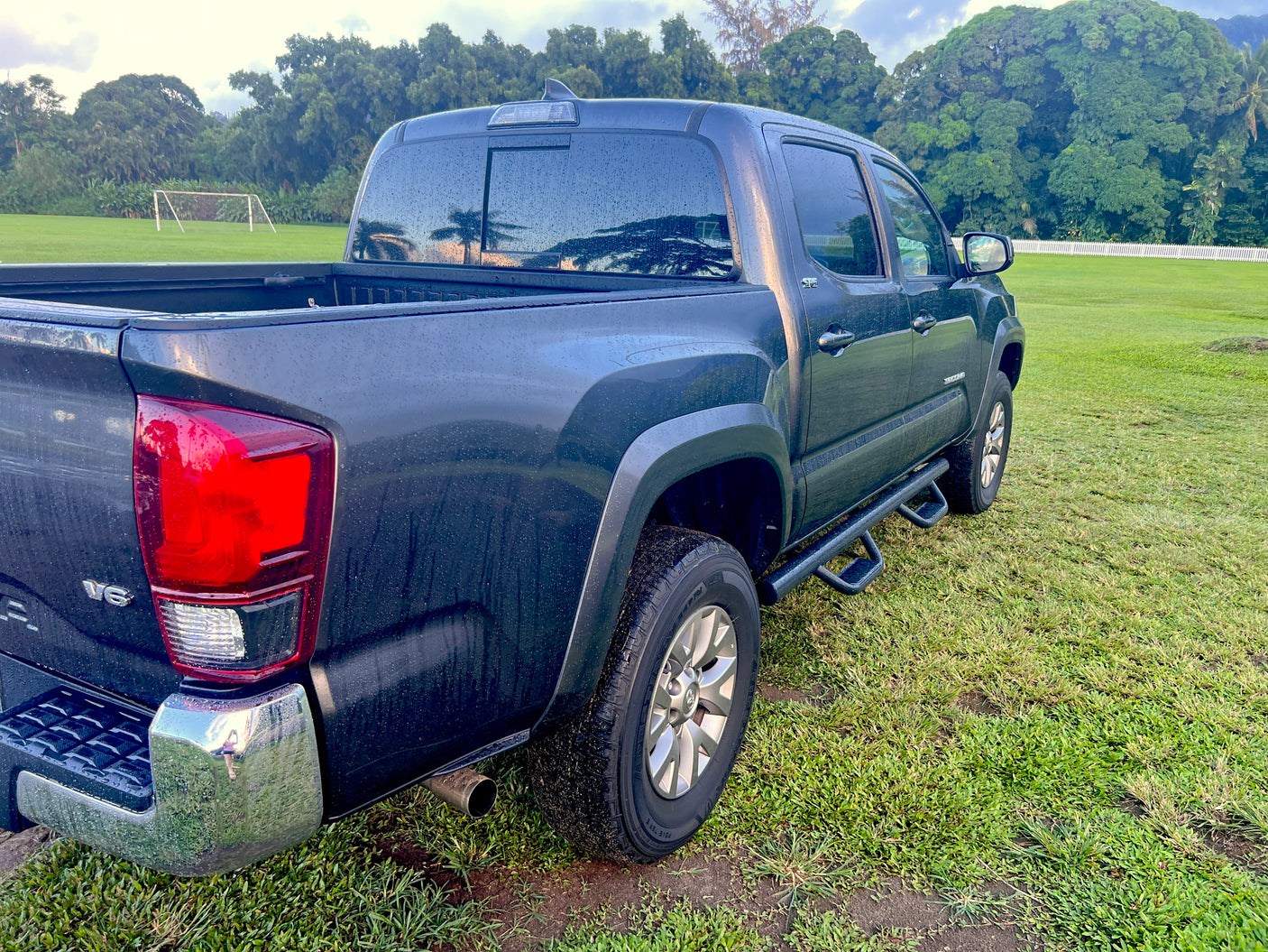 Adventure-ready dark pickup truck on green field near soccer goal. A great alternative to an RV rental for outdoor fun!