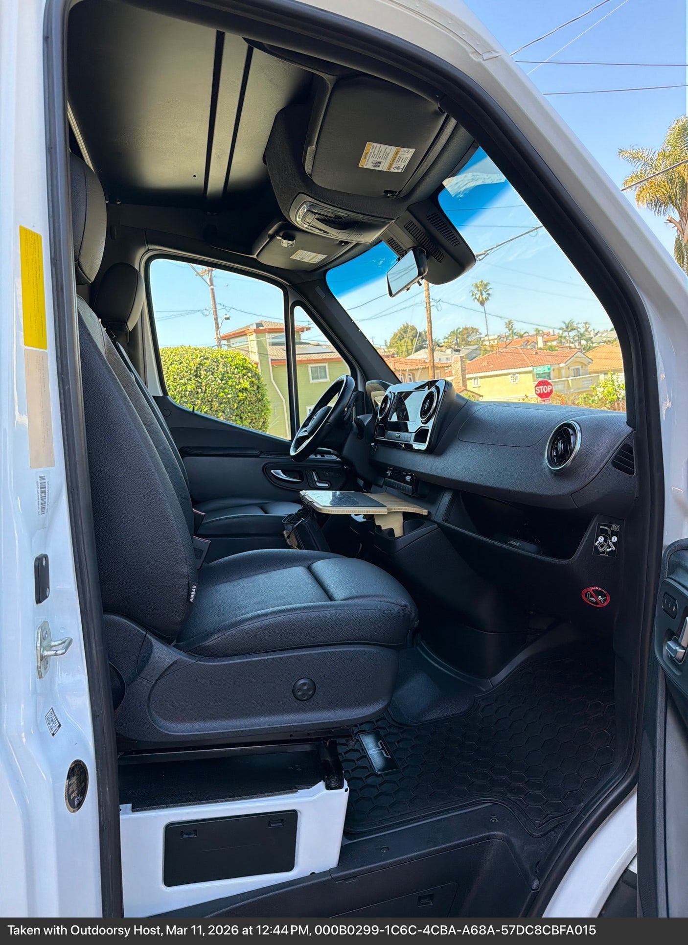 Explore the spacious front cabin of this RV rental, featuring a comfortable driver's seat, dashboard, and a convenient pull-out table.