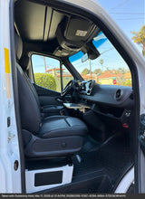 Explore the spacious front cabin of this RV rental, featuring a comfortable driver's seat, dashboard, and a convenient pull-out table.