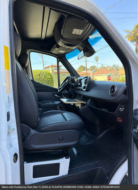 Explore the spacious front cabin of this RV rental, featuring a comfortable driver's seat, dashboard, and a convenient pull-out table.