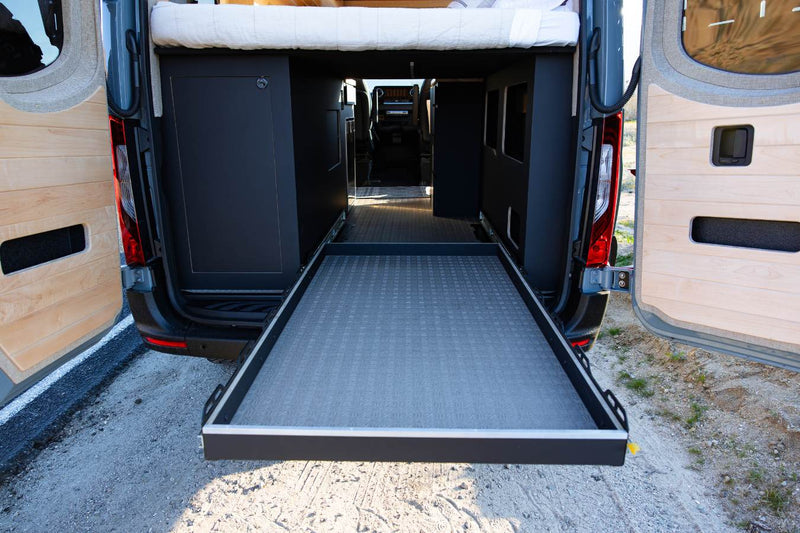  parked on a desert dirt road with rocky hills & Joshua trees.|RV rental: Modern camper interior shows a compact kitchen with induction cooktop & kettle — photo 20