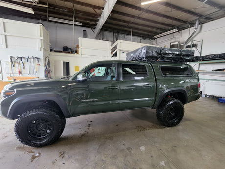 A lifted dark green Toyota Tacoma TRD truck, fitted with rooftop tents for exciting RV rental overlanding adventures.