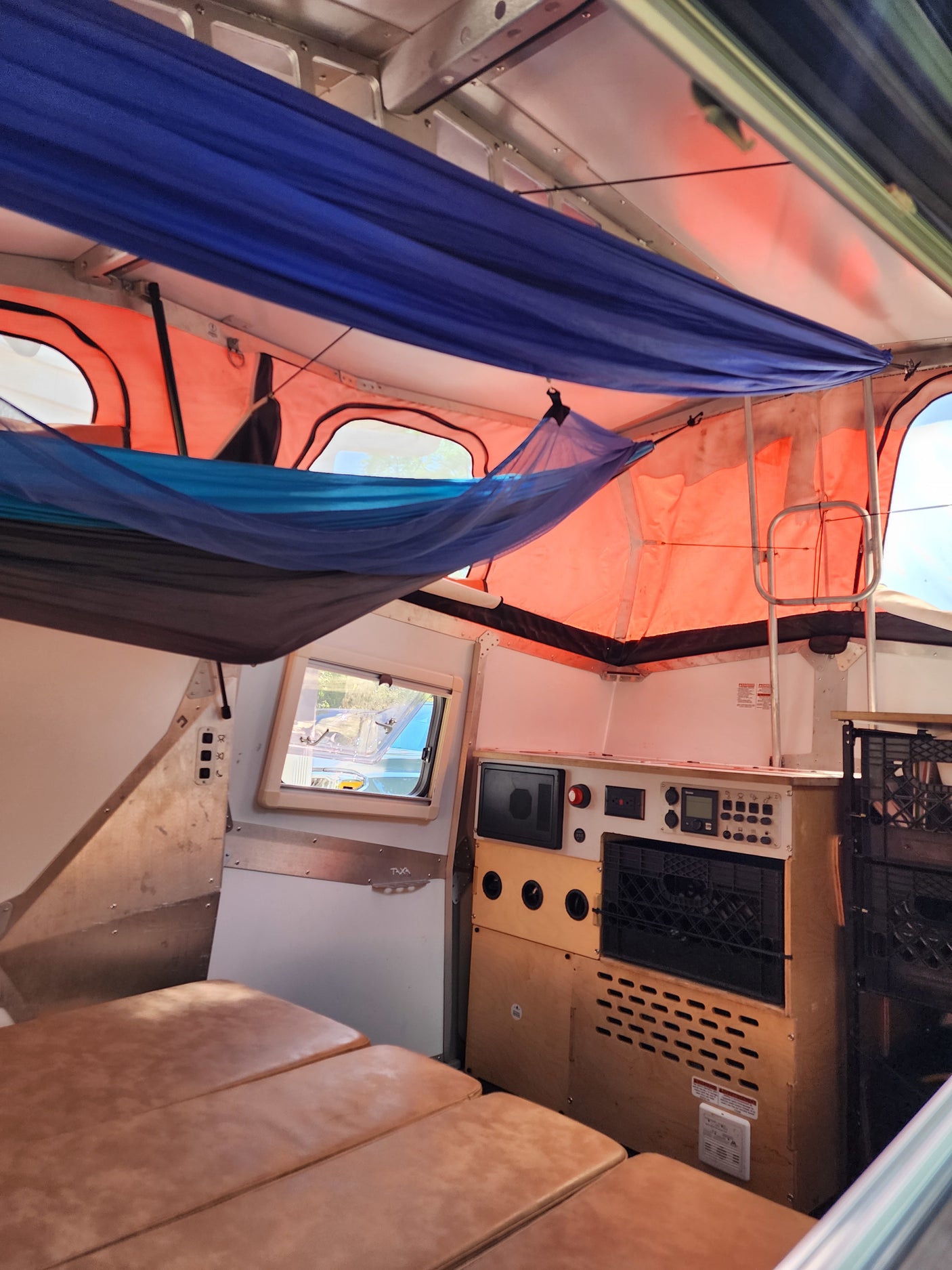 Experience comfort in this unique RV rental interior, featuring suspended hammocks, a convertible bed, and onboard controls.