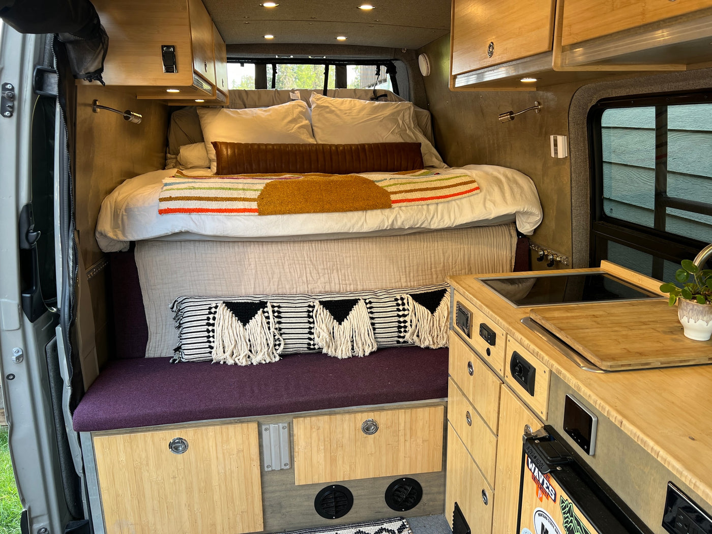 Inside an RV rental: a compact bed, kitchenette, and bamboo cabinetry for nomadic adventures. — photo 13