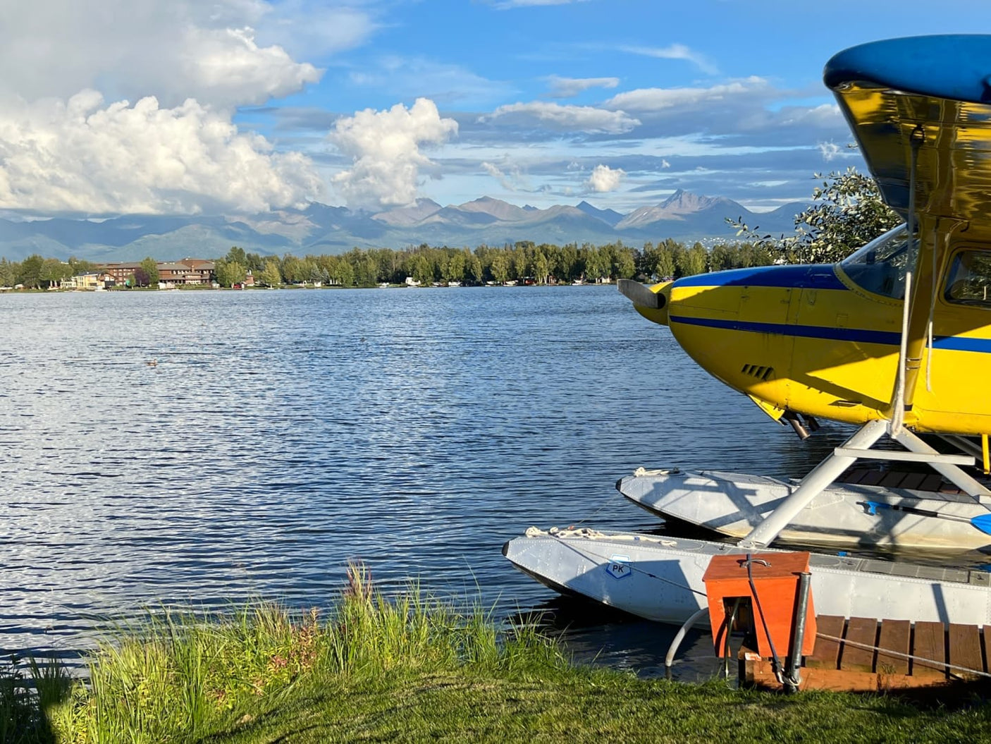 Yellow seaplane on an Alaskan lake with mountains beyond. Discover this beauty & more on your RV rental trip.