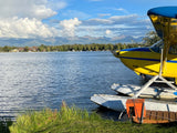 Yellow seaplane on an Alaskan lake with mountains beyond. Discover this beauty & more on your RV rental trip.
