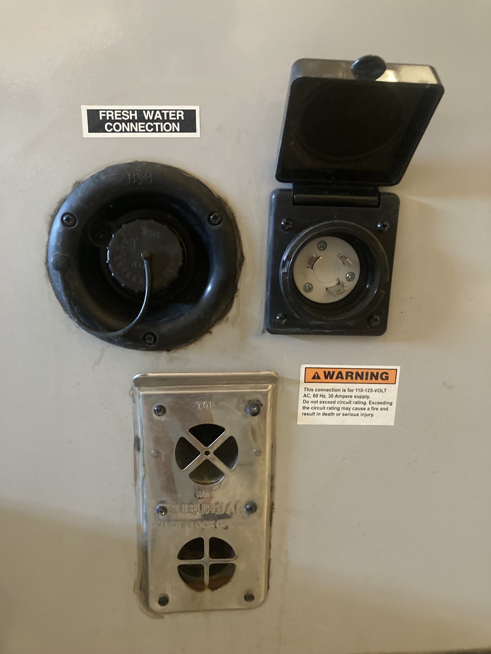 Essential RV rental exterior connections: fresh water inlet, 30A power hookup, and water heater vent.