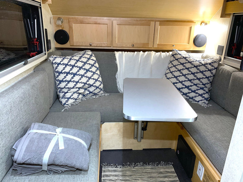 Step into this cozy RV rental's interior, featuring grey dinette seating, a central table, and overhead cabinets. — photo 3