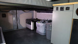 RV rental van interior features organized mobile living storage: portable power station, Yeti cooler, and cabinet controls.