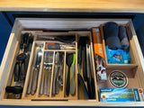 Inside an RV rental: a well-organized kitchen drawer with cutlery, cooking tools, aluminum foil, and wipes, ready for adventures.