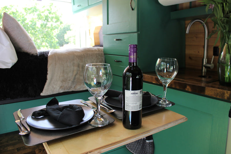 An RV rental interior featuring a table set for two with a bottle of CK Mondavi wine, glasses, and dinnerware. — photo 2
