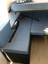This RV rental features a practical interior with an upper bunk bed & lower convertible seating/bed area with blue cushions.