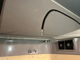 RV rental interior: pop-top fabric, dual USB ports, and a coiled hose (likely for light or shower) provide camper comfort.