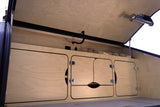 RV rental interior: Wooden cabinets, power outlets, storage, and light on the open pop-top roof.