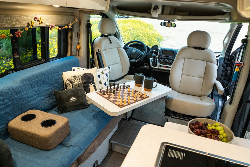 Cozy RV rental interior with a chessboard, sofa, and kitchen counter for travel and relaxation. — photo 8