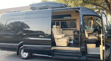 Luxury black RV rental with open doors showing a plush beige interior and custom captain's chairs, ideal for travel.