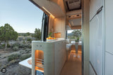 Explore nature in this stylish rv rental. Bright camper van interior features a modern kitchenette, dining, and scenic outdoor view.