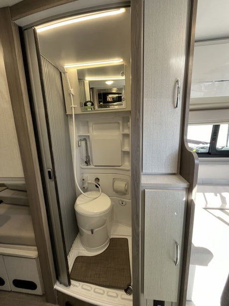 Compact RV rental wet bath with toilet, shower, and mirror, perfect for on-the-go living.