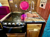  and decorative backsplash.|RV rental: Custom camper van interior with wood paneling