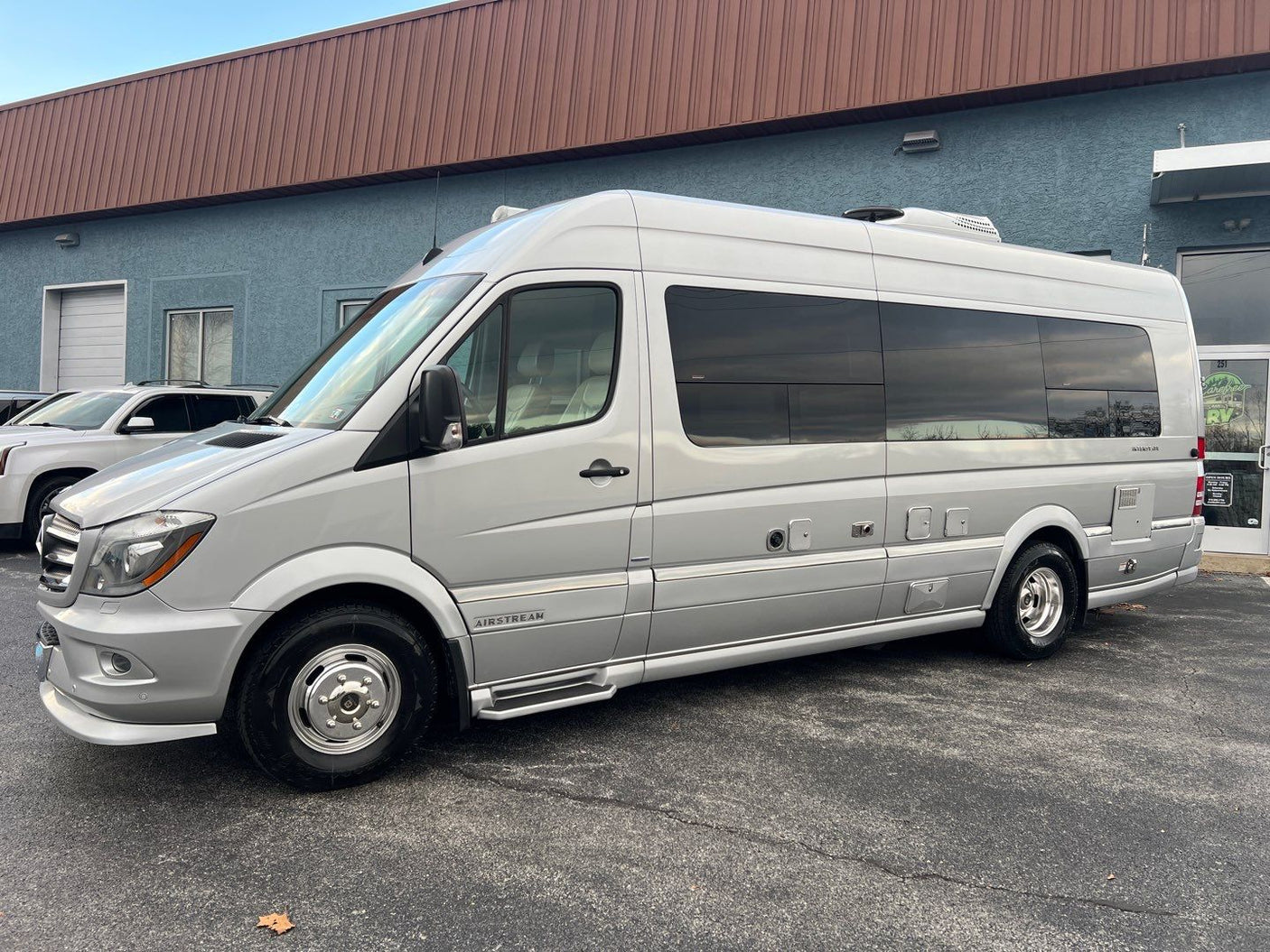 A sleek silver Airstream RV camper van, ideal for rv rental, is parked outside a store.