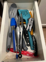 RV rental kitchen drawer: a collection of essential cooking utensils, including spatulas, tongs, knives, and a multi-tool.