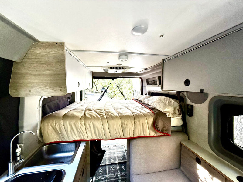  and large windows revealing a lush forest view.|A bright rv rental interior showcases a full kitchen — photo 6