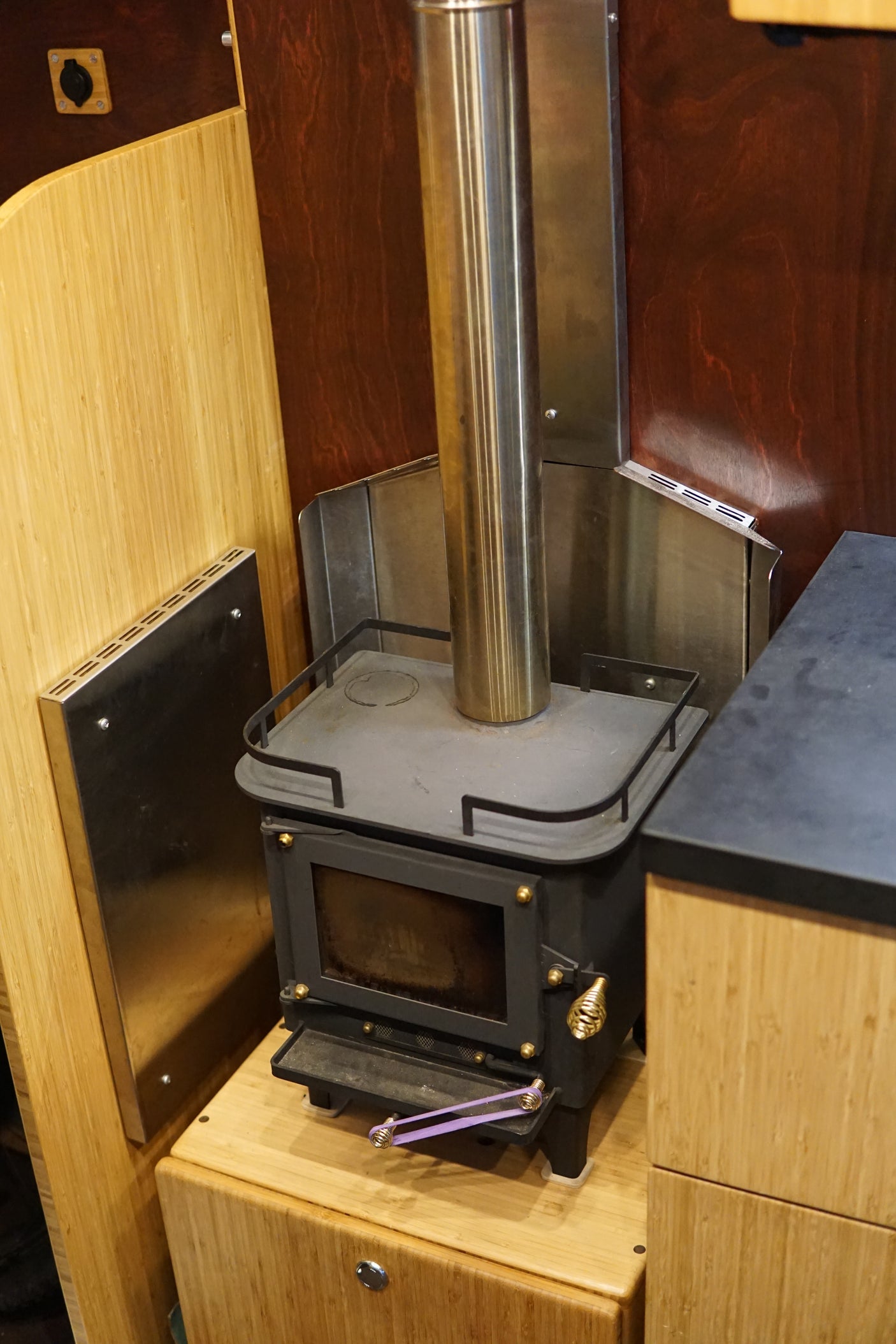 This compact wood stove with metal chimney and heat shields provides cozy heating in this RV rental's bamboo interior.