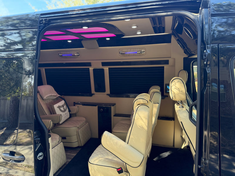 Inside our luxury RV rental: plush cream seats with black accents, vibrant magenta/blue lighting, and privacy shades for ultimate comfort. — photo 13