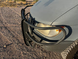 Adventure-ready gray RV rental with a black bull bar, off-road tire, and textured paint on a gravel path.