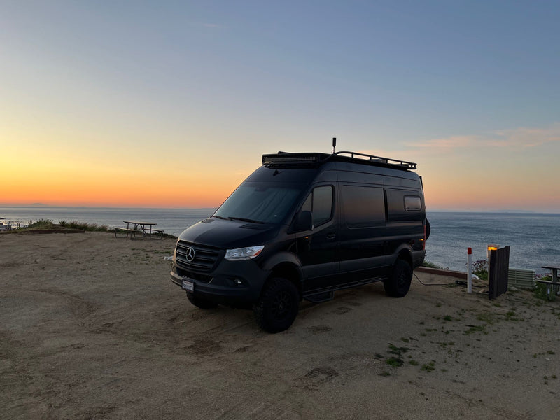 Black Mercedes-Benz Sprinter RV rental at sunset by the ocean. Ideal camper van for your next adventure or road trip. — photo 18