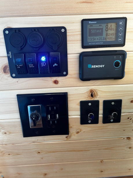 RV rental's electrical control panel: Renogy battery monitor, USB, outlets, and light switches for onboard power.