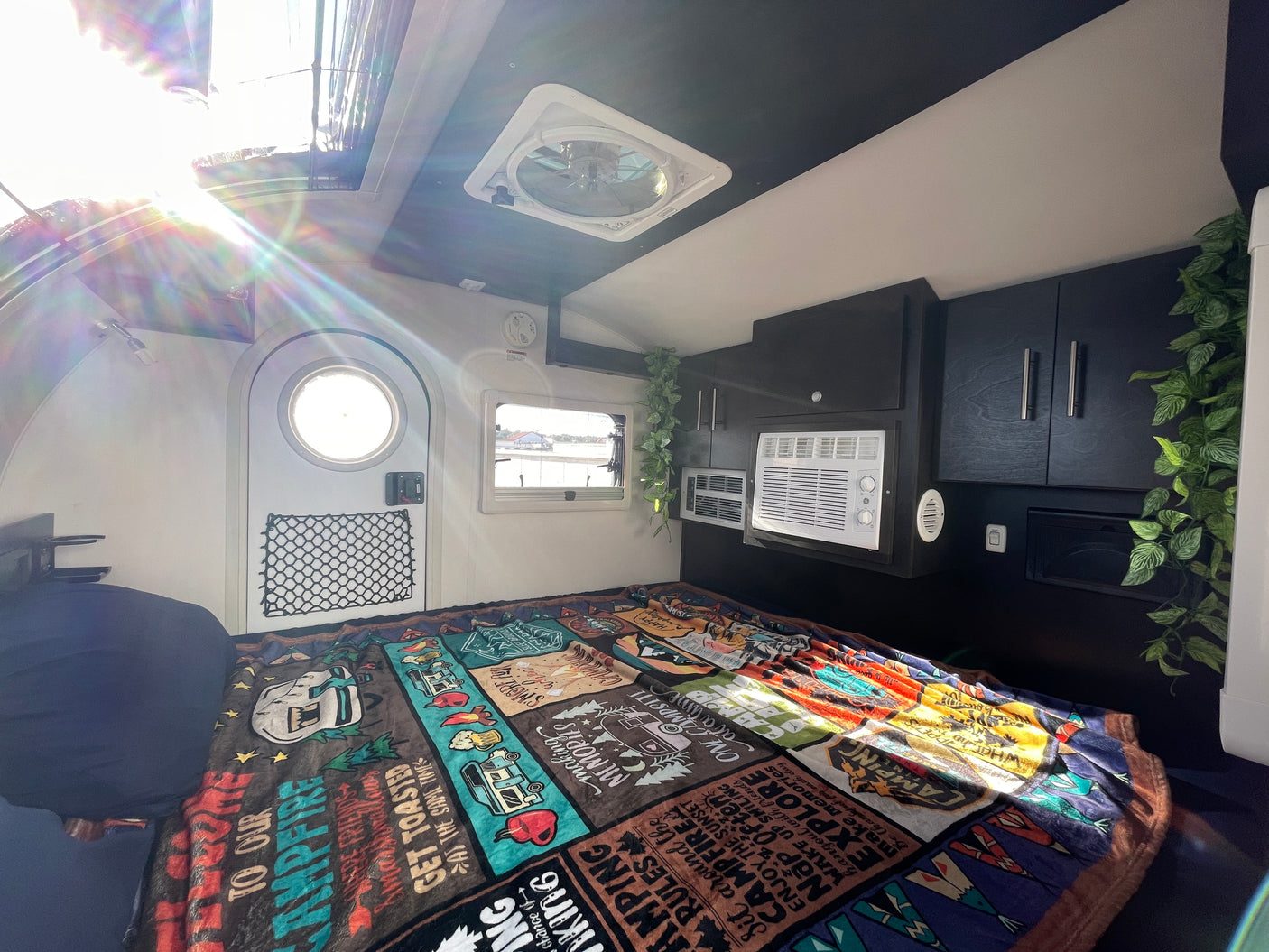 Step inside this bright RV rental! Features a comfy bed, AC, overhead fan, and windows, all in a compact camper interior.