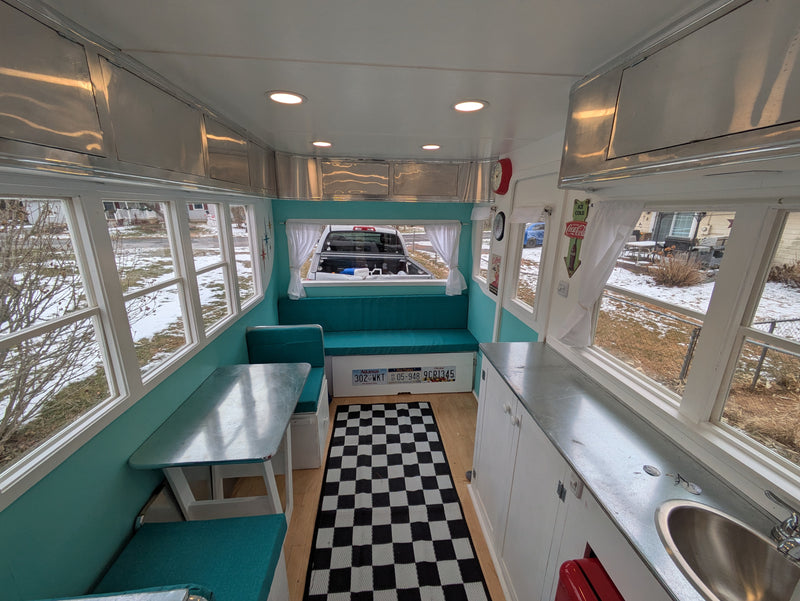 Retro teal diner-style RV rental interior with checkered rug, metal cabinets, and cozy booth seating. — photo 4