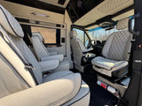 Luxury RV rental interior: white quilted leather seating, a screen, and a visible fire extinguisher for safety. Spacious & comfortable.
