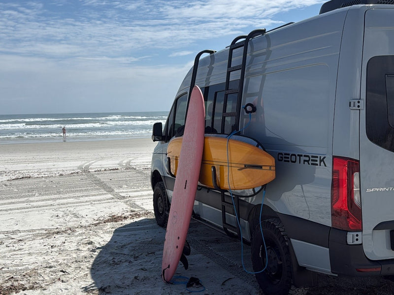  with dog shampoo nearby for their travels.|Light grey GEOTREK rv rental van on a sandy beach with two surfboards — photo 6