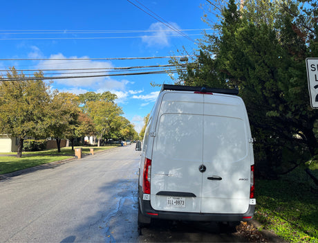 White Mercedes Sprinter van, often an RV rental, parked on a Texas residential street.