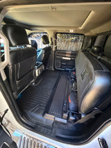 RV rental interior with rear seats folded up, revealing spacious cargo area, durable floor mats, and under-seat storage.