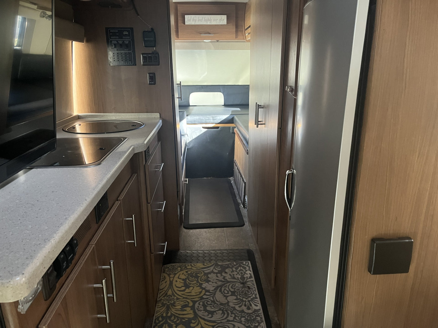 RV rental interior: A compact kitchen with a control panel leads to a hallway and rear living/sleeping area. — photo 15
