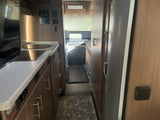 RV rental interior: A compact kitchen with a control panel leads to a hallway and rear living/sleeping area.