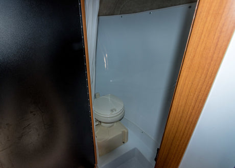 Compact RV rental bathroom with a white Dometic toilet and integrated shower space.