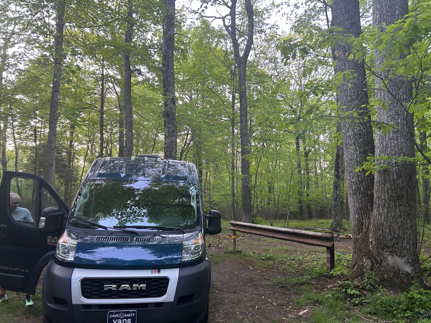 Dave & Matt Vans rv rental: A blue Ram ProMaster van, with a person entering, parked in a green forest for camping. — photo 5