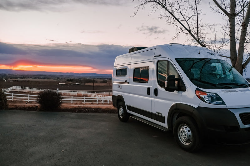 White Winnebago Solis Pocket RV rental at sunset, parked with a vibrant orange sky over a fenced valley. — photo 5