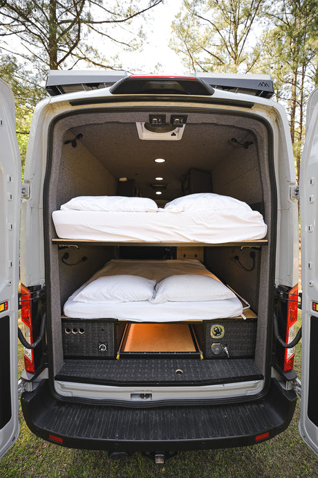 Inside a spacious RV rental, this custom camper van features bunk beds & smart storage for comfortable travel.